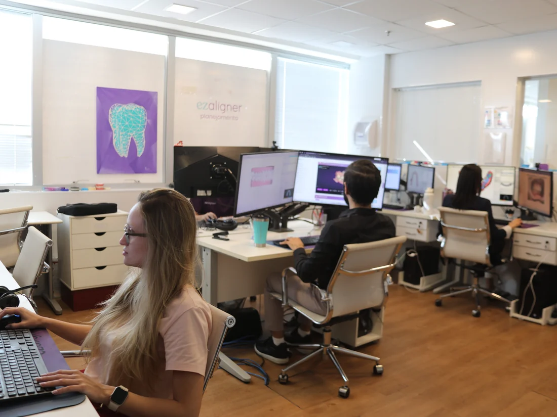 sala de planejamento da ezaligner com ortodontistas em estações 3d